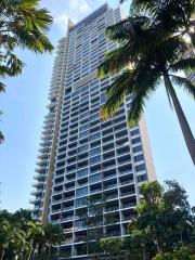 Modern high-rise residential building with balconies surrounded by palm trees
