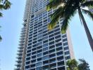 Modern high-rise residential building with balconies surrounded by palm trees