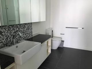 Modern bathroom with sleek design featuring dark floor tiles, a wall-mounted sink, mirror cabinet, and a toilet