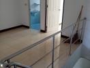 Stainless steel railing along a tiled staircase with doors leading to different rooms