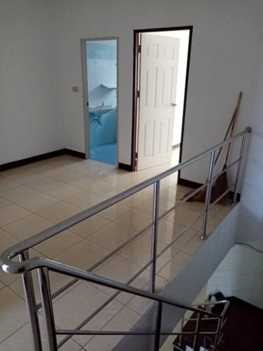 Stainless steel railing along a tiled staircase with doors leading to different rooms