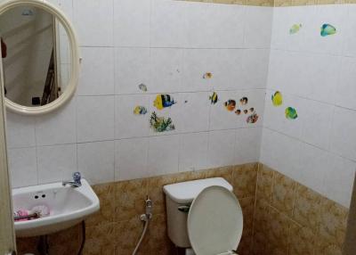 Compact bathroom with wall-mounted sink, toilet, and tiled decor