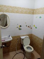 Compact bathroom with wall-mounted sink, toilet, and tiled decor