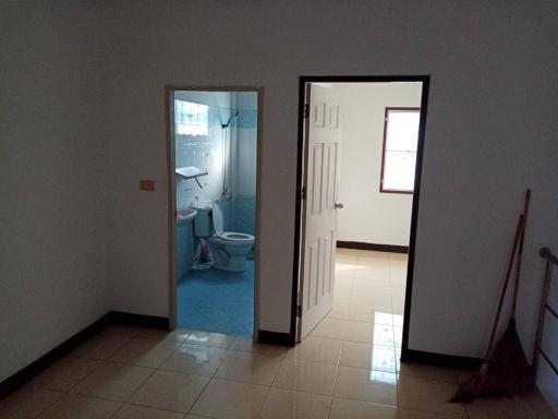 Hallway view with open doors to a bathroom and another room with tiled flooring