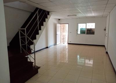 Spacious empty room with tiled flooring, staircase, and natural light