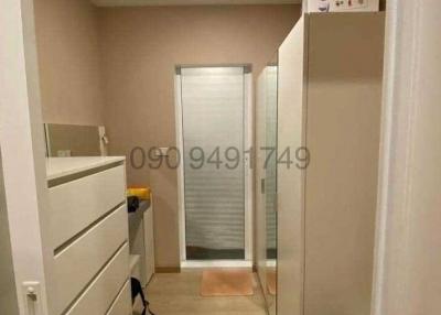 Hallway leading to a room with frosted glass door and storage furniture