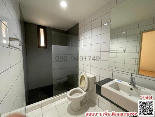 Modern bathroom with white tiles, shower area, and a toilet