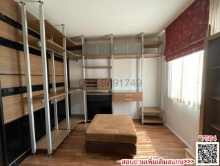 Spacious bedroom with natural light, featuring built-in shelving and an ottoman
