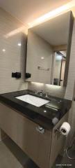 Modern bathroom with sleek finishes and well-lit mirror