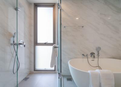 Modern bathroom with marble finish, featuring a walk-in shower and a separate bathtub