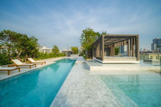 Luxurious rooftop swimming pool with city skyline view, sun loungers, and shaded seating area