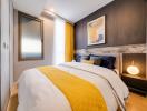 Cozy modern bedroom with stylish interior design, featuring a comfortable bed with yellow accents, artwork on the wall, and ambient lighting