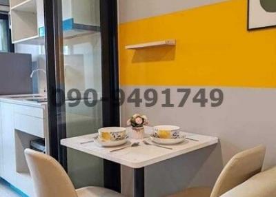 Modern dining area with two chairs and a small table against a vibrant yellow accent wall