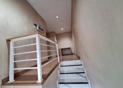 Modern staircase with wooden steps and white railing inside a home