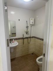 Compact bathroom with white fixtures and wall-mounted shower