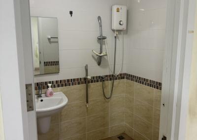 Compact bathroom with white fixtures and wall-mounted shower