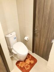 Modern bathroom interior with a clean toilet, beige tiles, and wooden door