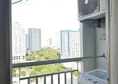 High-rise apartment balcony with outdoor air conditioning unit and washing machine overlooking cityscape