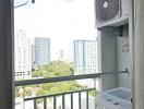 High-rise apartment balcony with outdoor air conditioning unit and washing machine overlooking cityscape