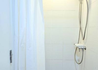 Clean white tiled bathroom with shower curtain and modern shower head