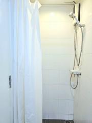 Clean white tiled bathroom with shower curtain and modern shower head