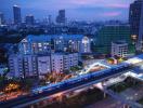 Aerial view of a cityscape at dusk with buildings and a moving train