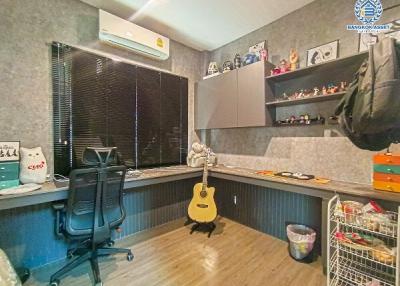 Home office with desk, guitar, and decorative shelving