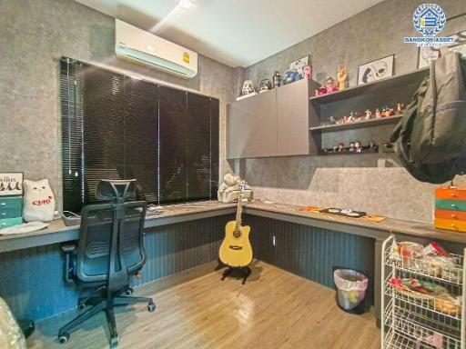 Home office with desk, guitar, and decorative shelving