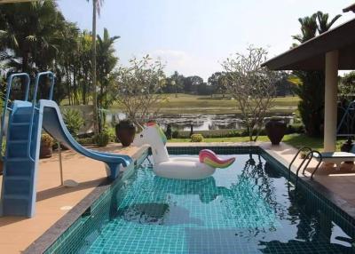 Private pool with a waterslide and inflatable unicorn overlooking a scenic pond
