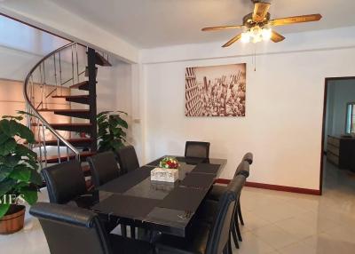 Spacious dining room with a modern table, staircase, and ceiling fan