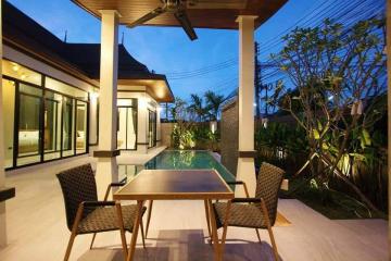 Modern patio with a dining table and pool view at dusk