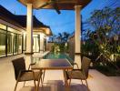 Modern patio with a dining table and pool view at dusk