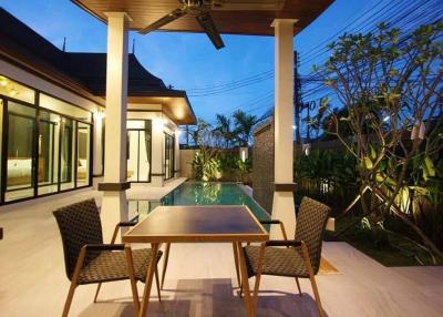 Modern patio with a dining table and pool view at dusk