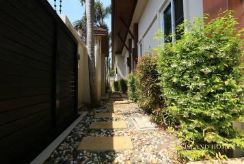 Paved garden pathway with green shrubs and privacy fence in a residential property