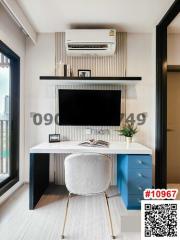 Modern home office with desk and chair, large TV or monitor, and air conditioning unit