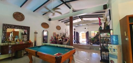 Spacious and well-furnished living room with pool table and high ceiling