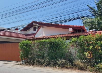 Exterior view of a residential house with a gate and landscaping