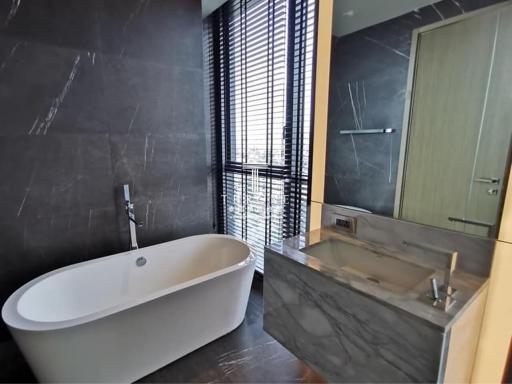 Modern bathroom with freestanding tub, glass-enclosed shower, and large window with blinds