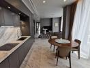 Modern kitchen with marble countertops and open-concept design leading to the living and dining area