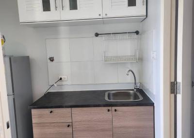 Compact kitchen with white upper cabinets and wooden lower cabinets