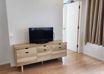 Minimalist styled bedroom with wooden flooring and television set