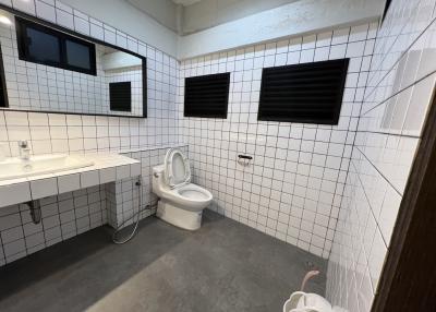 Modern bathroom with white tiling, wall-mounted sink, and toilet