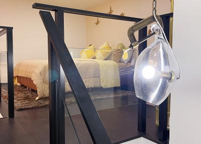 Modern bedroom interior with glass pendant light, black metal railing, and yellow accent pillows