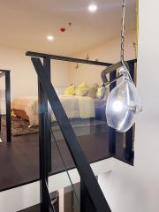 Modern bedroom interior with glass pendant light, black metal railing, and yellow accent pillows