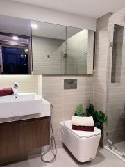 Modern bathroom with beige tiles, wood vanity, and white fixtures