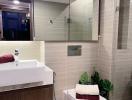 Modern bathroom with beige tiles, wood vanity, and white fixtures