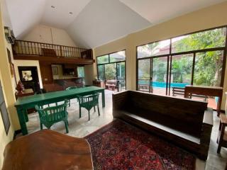 Spacious living room with high ceilings, abundant natural light, and pool view