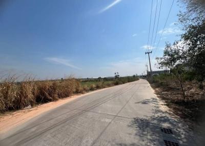 Paved road with surrounding open land under clear sky