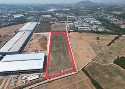 Aerial view of a large rectangular plot of land outlined in red near industrial buildings
