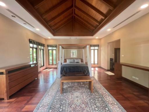 Spacious bedroom with hardwood floors, high ceiling, and ample natural light
